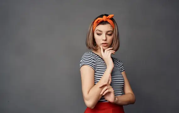 Симпатичная женщина в полосатой футболке, на голове оранжевая повязка, модные эмоции