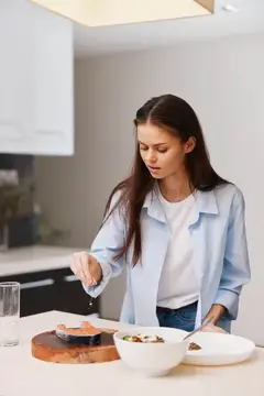 Молодая женщина готовит салат на светлой кухне