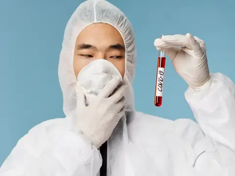 Мужчина в защитном костюме держит пробирку с анализом на COVID-8