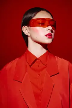 Азиатская девушка в красных очках и костюме на красном фоне