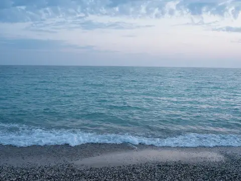 Спокойное море с легкой волной и галечным пляжем под облачным небом