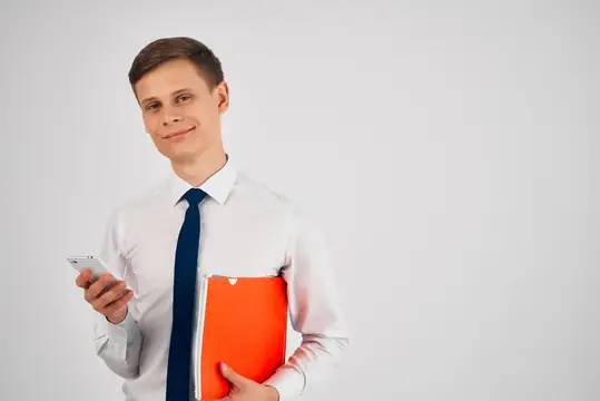 Молодой человек в белой рубашке с телефоном и оранжевой папкой