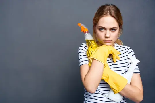Уставшая женщина в жёлтых перчатках с чистящим средством