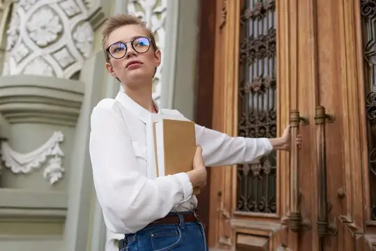 Привлекательная женщина стоит на улице возле здания, отдыхает и учится