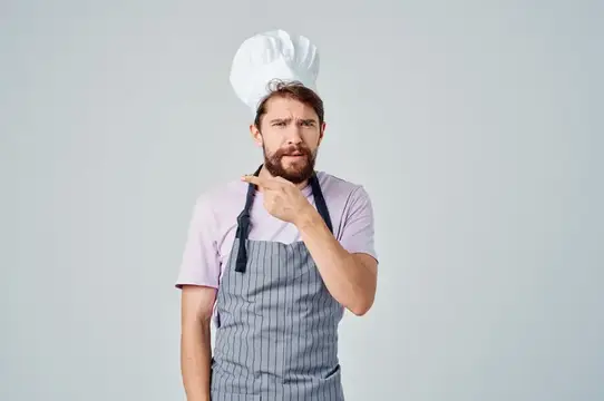 Задумчивый бородатый повар в колпаке и фартуке