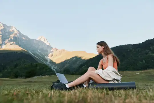 Девушка работает за ноутбуком на фоне гор
