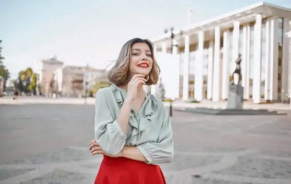 Улыбающаяся женщина в блузе на фоне городской площади