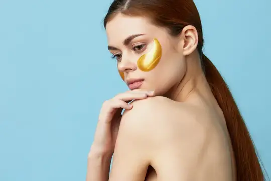 Портрет женщины с золотыми патчами на лице на изолированном фоне