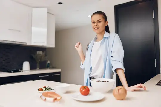 Улыбающаяся девушка готовит завтрак на светлой кухне
