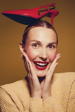 Улыбающаяся женщина с красной туфлей на голове