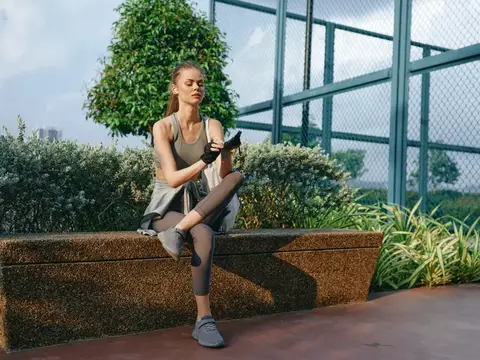 Спортивная девушка отдыхает на каменной скамье после тренировки