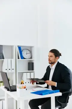 Мужчина с длинными волосами работает с документами в светлом офисе