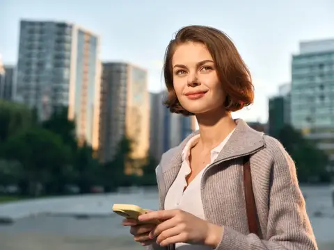 Молодая женщина с телефоном на фоне городских высоток