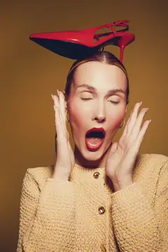 Удивлённая женщина с красной туфлей на голове