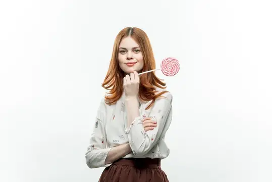 Рыжеволосая девушка с розовым леденцом на белом фоне