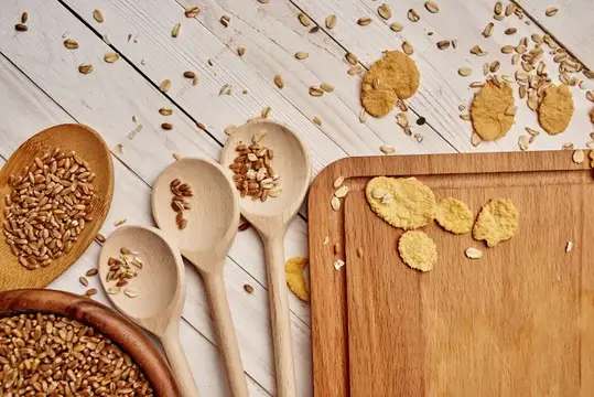 Деревянные ложки с зернами и овсяное печенье на доске