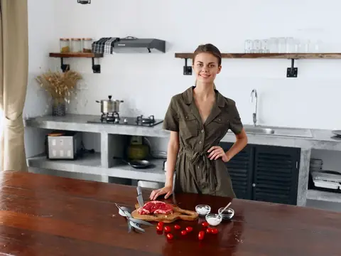 Улыбающаяся женщина в платье с поясом у кухонного стола с помидорами