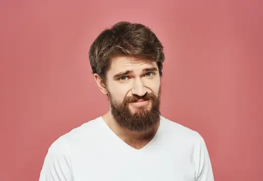 Грустный мужчина на розовом фоне, кадрированный вид: белая футболка и густая борода