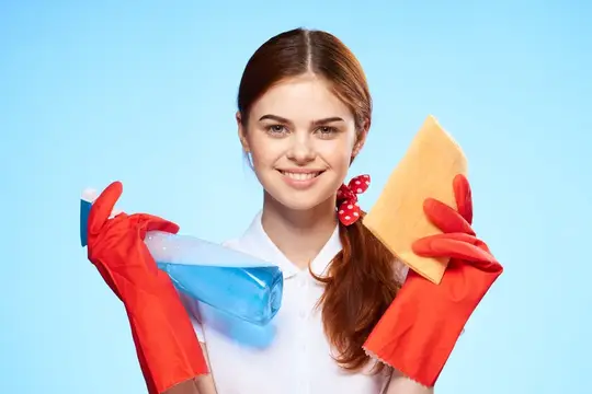 Улыбающаяся девушка в красных перчатках с чистящими средствами
