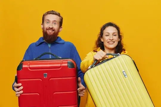 Улыбающиеся женщина и мужчина с чемоданами в руках — жёлтым и красным — весело и криво улыбаются на жёлтом фоне, собираются в путешествие, семейная отпускная поездка, молодожёны