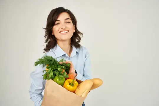 Брюнетка с пакетом продуктов из супермаркета: здоровая еда, овощи