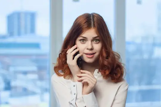 Рыжеволосая женщина разговаривает по телефону в офисе, бизнесвумен, менеджер