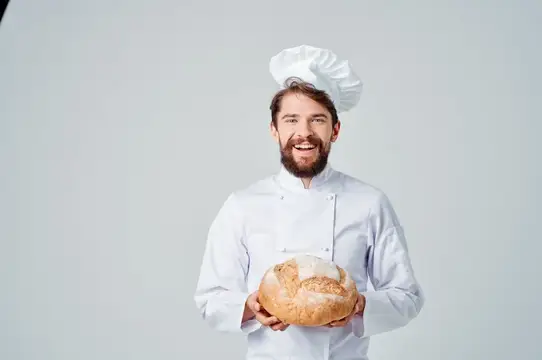 Повар-мужчина на кухне, работа в пекарне, выпечка на светлом фоне