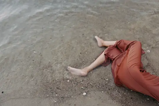 Босые ноги лежащего человека в шелковой одежде у воды