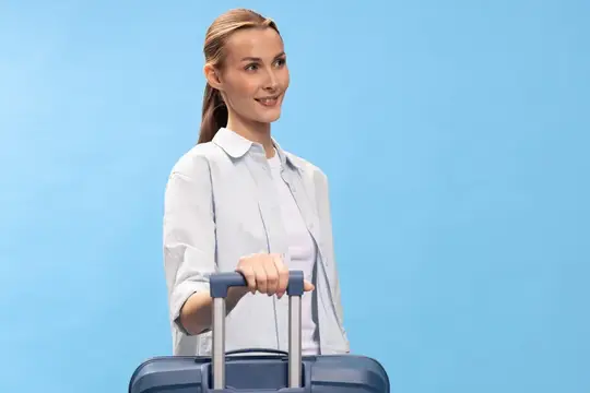 Улыбающаяся светловолосая женщина с чемоданом на голубом фоне