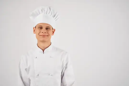 Весёлый шеф-повар-мужчина работает на кухне ресторана