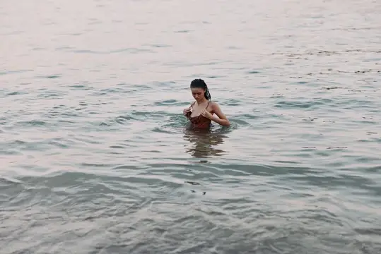Молодая женщина стоит по грудь в воде спокойного моря