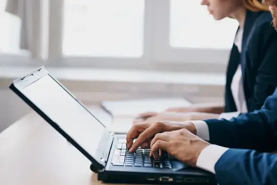 Мужчина и женщина в деловых костюмах работают за ноутбуком