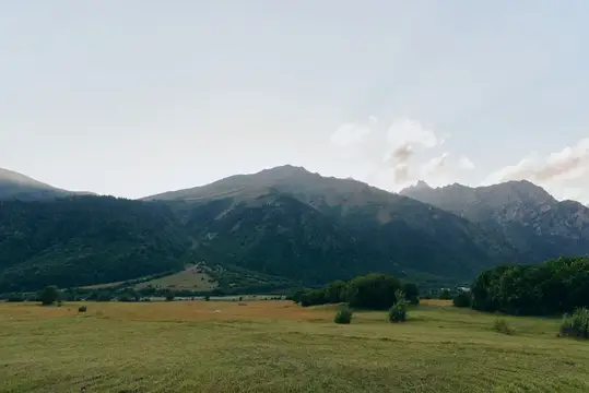 Горный пейзаж с зелёной долиной и облачным небом