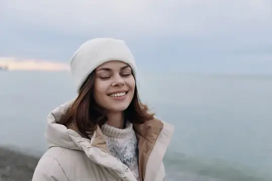 Улыбающаяся девушка в белой шапке на берегу моря