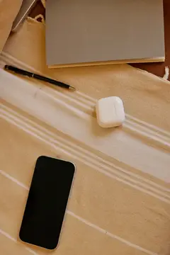 Смартфон, наушники и блокнот на бежевой ткани