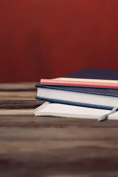 Стопка книг и блокнот с ручкой на деревянном столе