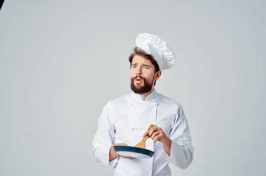 Профессиональный повар жарит еду на сковороде, работая на кухне