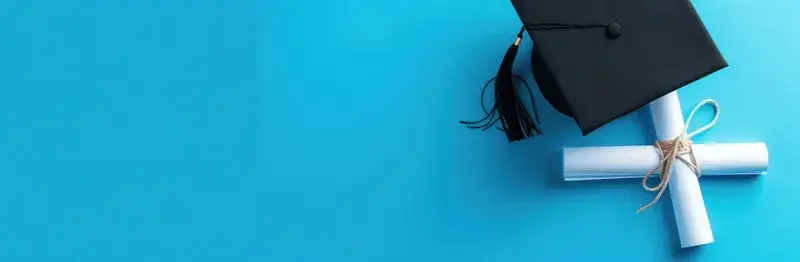 Чёрная выпускная шапочка и диплом с лентой на синем фоне