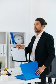 Мужчина с хвостом в костюме держит папку с документами в офисе