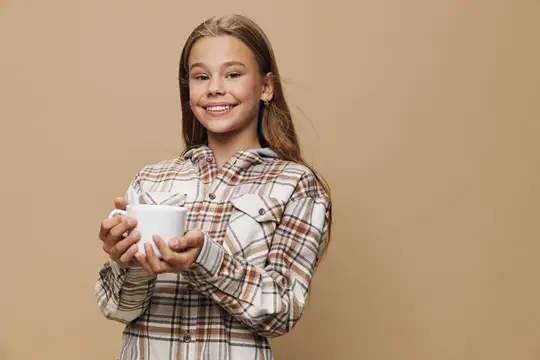 Улыбающаяся девочка с длинными волосами держит белую кружку