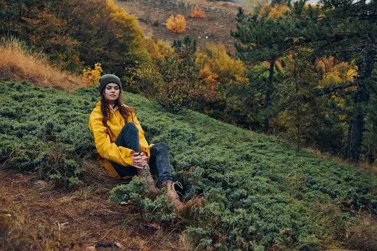 Молодая женщина в жёлтой куртке отдыхает на осеннем склоне