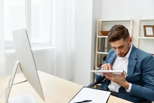 Мужчина в синем пиджаке работает с планшетом в светлом офисе