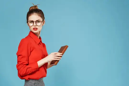 Молодая женщина в красной рубашке с книгой на голубом фоне