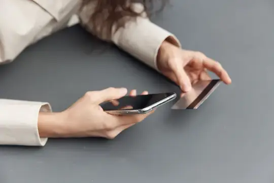 Женские руки держат смартфон над серым столом