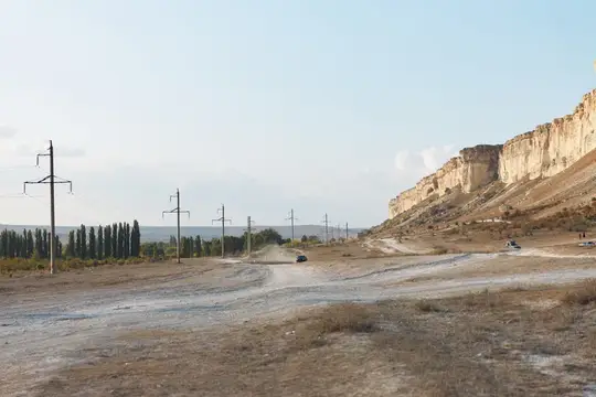 Живописная дорога, вьющаяся среди величественных гор под голубым небом с белыми облаками в дневное время