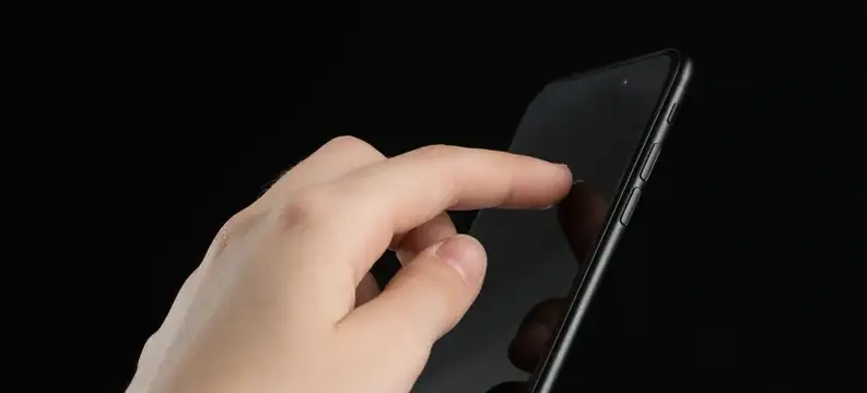 Рука касается экрана смартфона на чёрном фоне