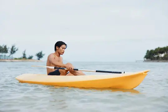 Азиатский мужчина катается на байдарке в тропическом раю: приключения на пляже