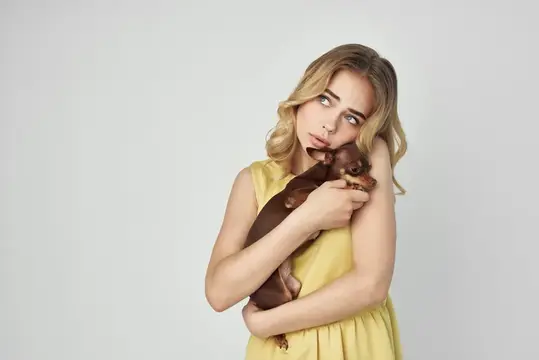 Красивая женщина с модной породистой собакой на светлом фоне в студии