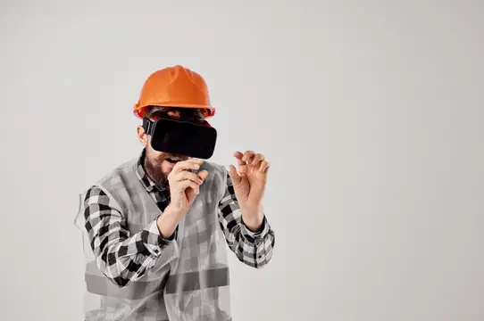 Строитель в оранжевой каске и VR-очках на сером фоне