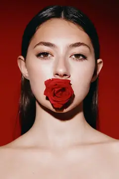 Азиатская девушка с красной розой у губ на красном фоне